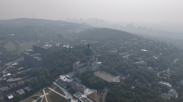 Hazy aerial view of Westmount and downtown Montreal skyline hidden behind smog and trees. c.