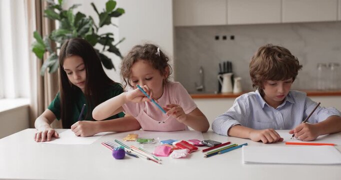 Children sitting at kitchen table drawing with colored pencils, engaging in creative activity during family leisure time. Kids developing artistic skills, enjoying indoor hobby at home with siblings