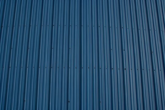 Blue corrugated metal roof texture with vertical lines and rivets