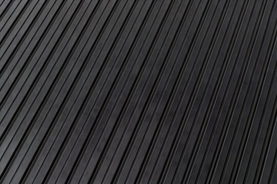 Abstract industrial black corrugated metal roofing sheet texture background with diagonal steel ridges and dark metallic surface cladding