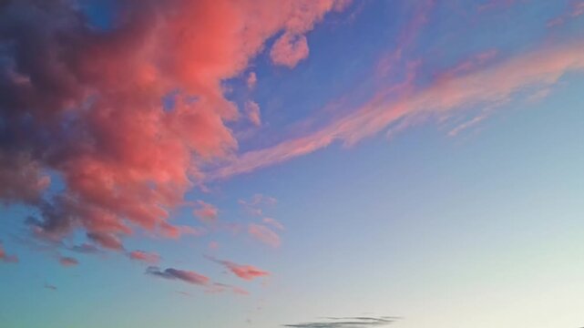 Beautiful pink and blue sunset sky with soft drifting clouds at golden hour.