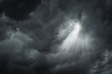 Obraz premium Rays of light through the dark, ominous, stormy clouds.