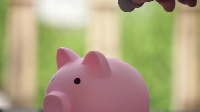 Hand is Saving money in piggy bank, close-up financial concept for investment, banking and wealth growth.