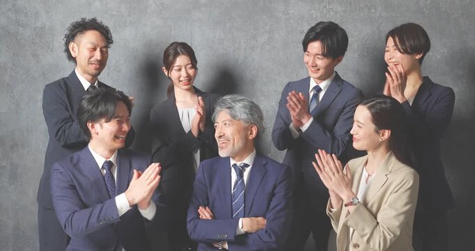 ノートパソコンの前に集合する様々な世代のスーツを着た男女
