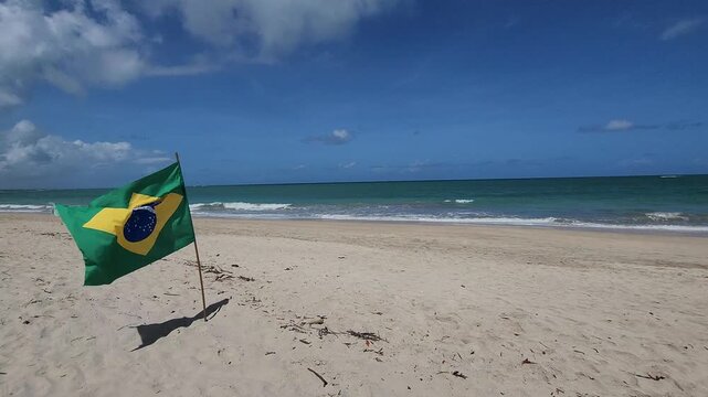 Brazil flag on a white sand beach with turquoise water in the State of Pernambuco.	