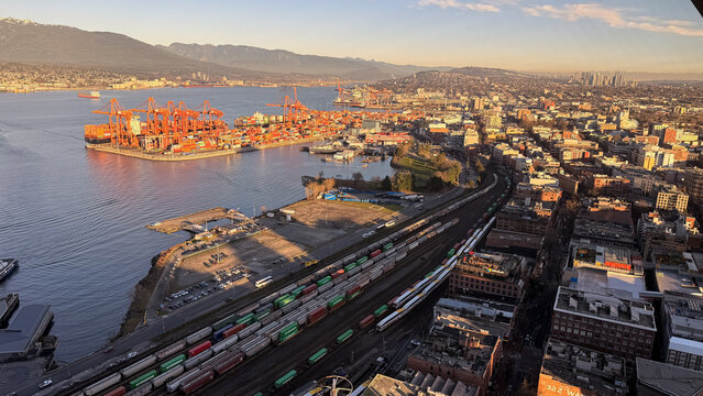 Aerial view of Vancouver port with container cranes and railway yards at golden hour