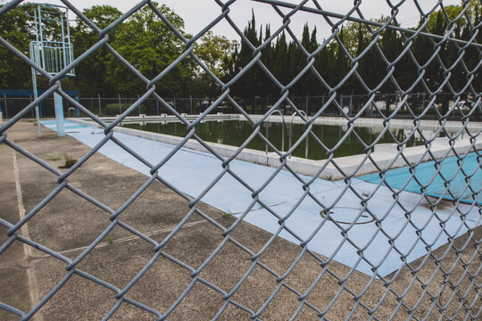 Chain link fence in front of abandoned swimming pool