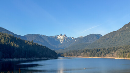 Fototapeta premium Cleveland Dam reservoir with The Lions peaks and North Shore Mountains, Vancouver