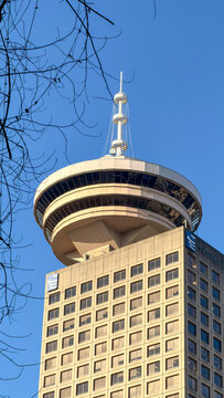 Vancouver, Canada - January 2026: Vancouver Lookout observation tower atop Harbour Centre skyscraper against clear blue sky with bare winter branches
