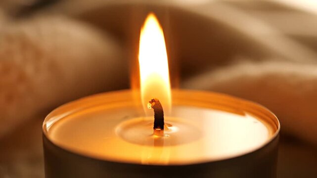 Close up of a lit tea light candle with a warm orange flame