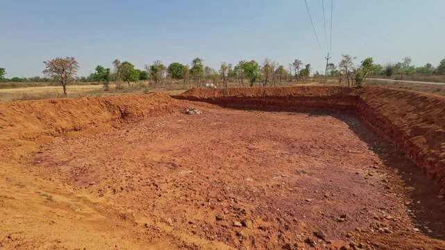 Panning shot of a farm pond or Khet Talab excavated in agricultural land for rainwater harvesting and irrigation in a rural countryside landscape!