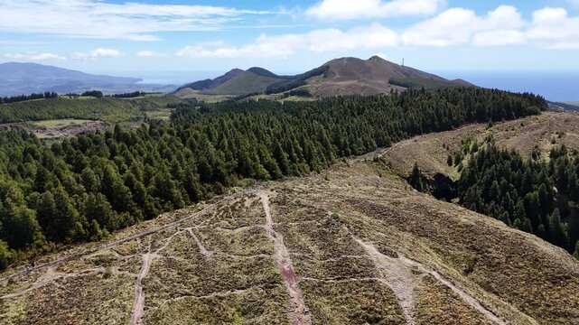 High altitude drone view of the mountain ridges and hiking trails surrounding Sete Cidades on Sao Miguel, Azores. Rugged volcanic terrain overlooking the lush green caldera and blue horizon