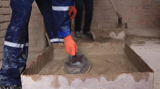 A student in a training workshop practices practical skills in preparing cement mortar.