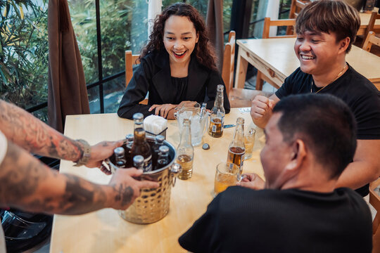 A young asian girl was surprised in a second round bucket of beer with her friends at the bar. expressing excitement and delight