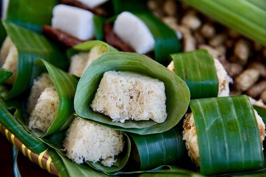 Close-up shot of traditional Indonesian sweet cassava cakes (getuk) topped with grated coconut and wrapped in fresh banana leaves.