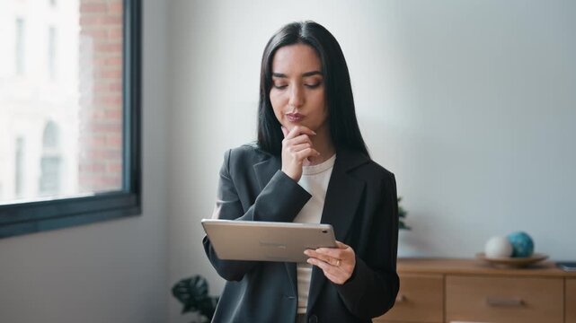 Video of elegant businesswoman working with digital tablet while standing in the office