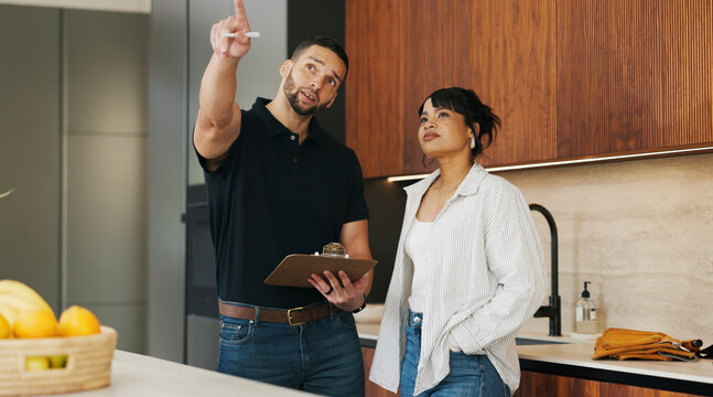 Checklist, discussion and handyman with woman in kitchen for maintenance, service or home renovation. Installation, inspection or man with clipboard for client information, pointing or invoice