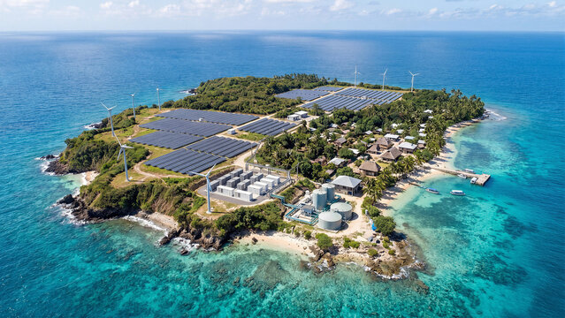 Aerial view of self sufficient tropical island with solar panel farm wind turbines battery storage and water treatment beside resort villas showcasing sustainable microgrid renewable energy infrastruc