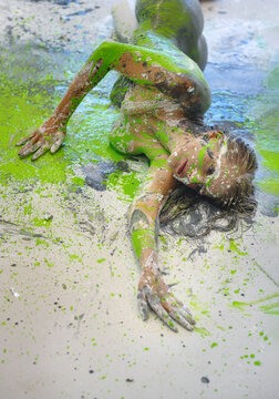 Person lying on studio floor with vivid green paint splashes creating abstract textures, dynamic composition and expressive artistic scene with strong visual energy.