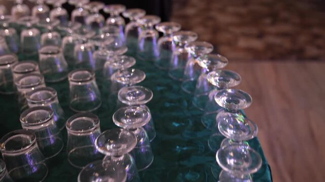 Empty glasses arranged in neat rows on a patterned green tablecloth create an elegant professional setup for a festive evening banquet.