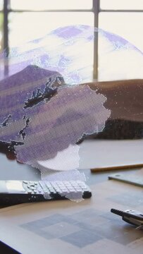 Vertical video: Hands entering, clasping, shaking, releasing to seal deal, globe drifting over desk