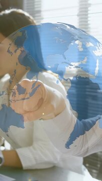 Vertical video: Woman handling docs at desk while peer arm entering tapping globe showing biz data