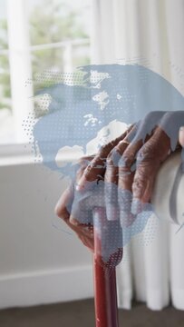 Vertical video: Senior woman resting hands on red cane by pane shifting grip as map overlaying care