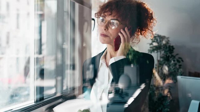 Video of elegant business woman working while talking with smartphone in the office