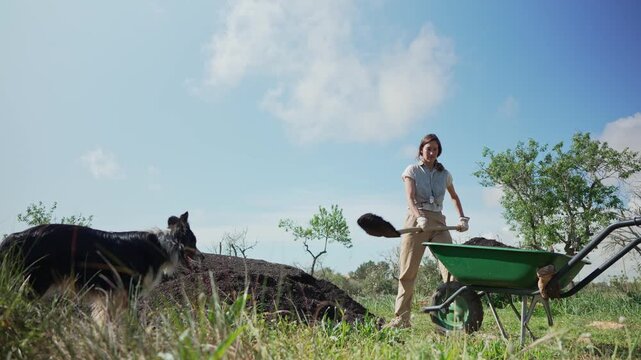 Female farmer shoveling compost into a wheelbarrow