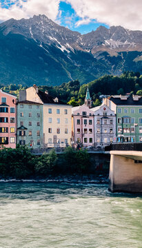 Atmospheric sunset view over the Inn River in Innsbruck Austria with colorful historic houses, dramatic clouds and alpine mountain scenery in the background. Beautiful European cityscape in Tyrol duri