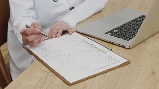 Close-up of Hands of Female Doctor Filling in Medical Questionnaire