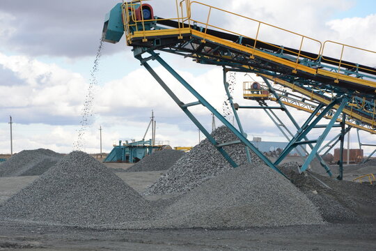 Process of dropping gravel from industrial conveyor belt onto heap at mineral open pit quarry