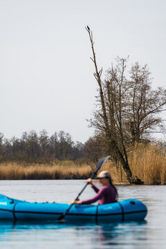 Woman Paddling a Packraft on the Peene with Cormorant on Dead Tree