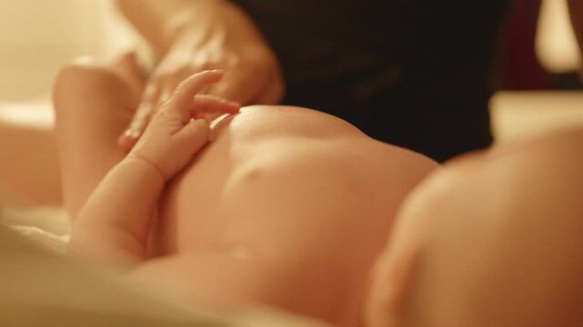 Mother applies cream or balm to her baby tummy. Close-up