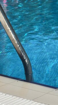 Pool edge tiled with slip-resistant ceramic or porcelain tiles, often bullnosed for safety, surrounding vibrant blue water in a resort or residential setting.