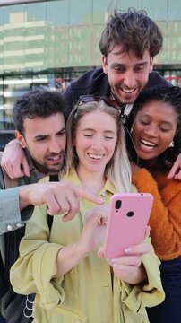 A group of joyful friends is gathered closely together, sharing laughter and excitement while engaging with a smartphone, creating a memorable moment of connection and happiness among them.