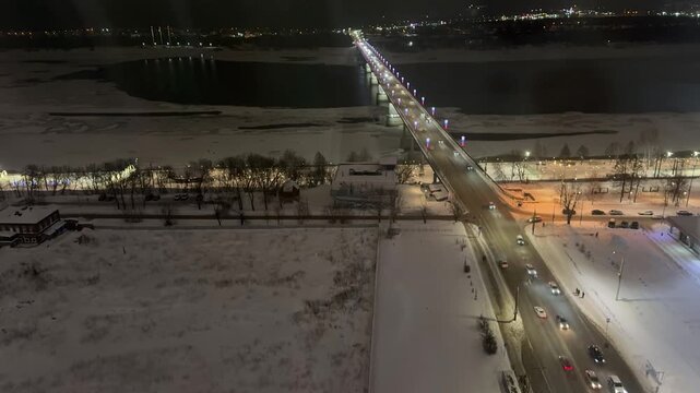 Evening timelapse captures a city bridge over river glowing with colorful illumination as traffic streaks light trails in the twilight urban scene.