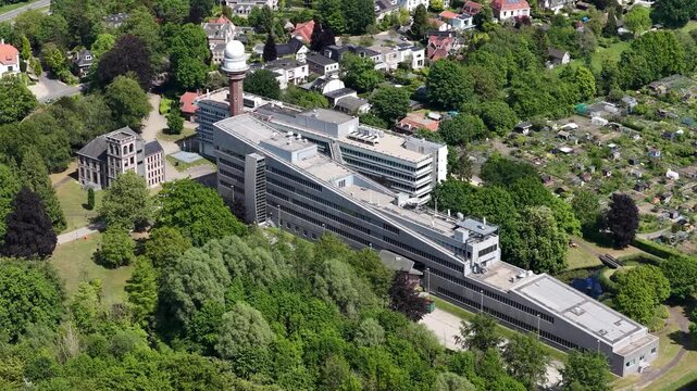 High angle drone view of the royal netherlands meteorological institute - knmi - complex in de bilt, radar tower and modern buildings amid lush trees and surrounding residential area