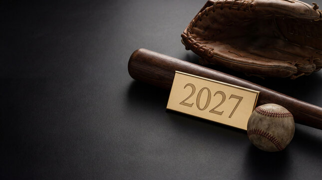 2027 brass plaque beside baseball bat glove ball on dark surface for sports season opening commemorative trophy concept athletics marketing banner with nostalgic clubhouse mood copy space
