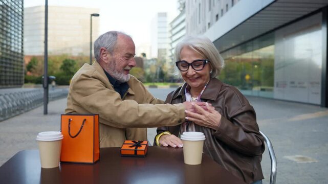 Senior couple arguing then reconciling at a cafe