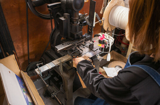 Worker operating vintage press machine for lead wire cutting in small metal factory
