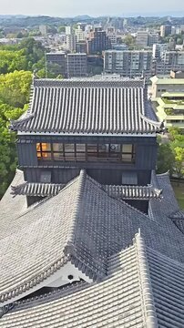 Japanese feudal castle tenshu rooftop with kumamoto city skyline, Medieval Feudal Japan, Historical Landmark, Samurai Fortress, Travel Landmark, Panning Up Shot