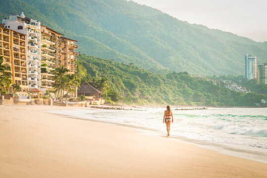 Mexico, Puerto Vallarta, woman wearing bikini walking at the Punta Negra beach
