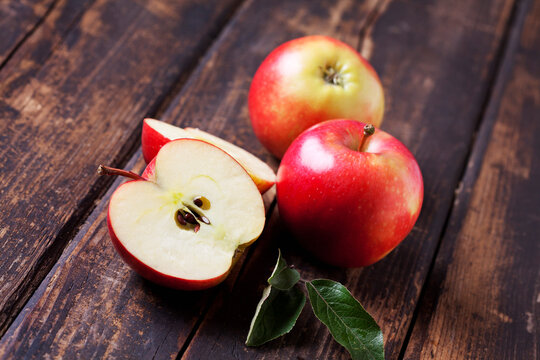 Whole and sliced red apples on dark wood