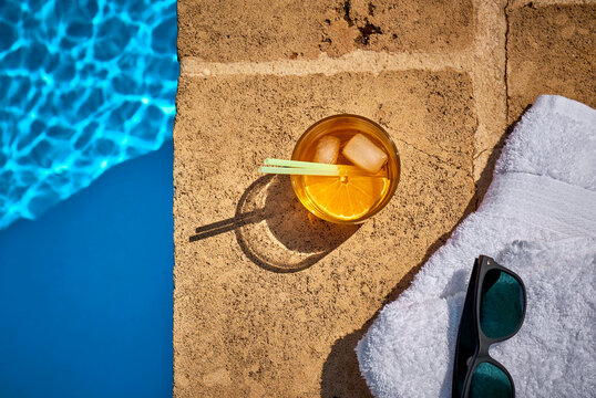 Glass of Crodino, sunglasses and towel at the poolside