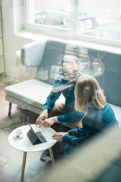 Businessman and businesswoman with tablet discussing in office lounge