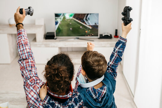 Father and son playing computer game at home