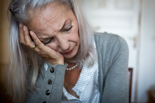 Portrait of sad woman with head in her hand at home