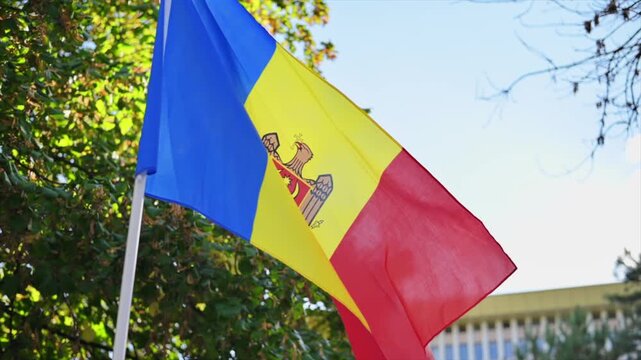 Moldovan national flag waving in wind against blue sky.