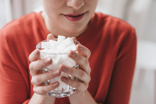 Close-up of woman holding glass full of sugar cubes